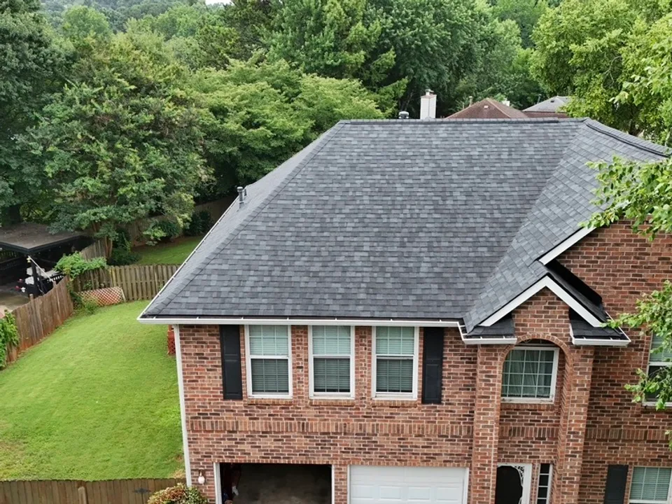 Aerial view of a brick home with a newly installed charcoal shingle roof